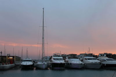 Boats moored in river against cloudy sky at dusk