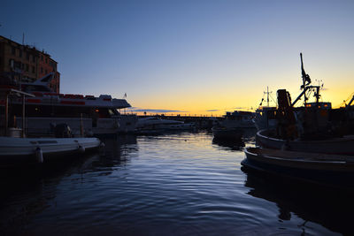 Ship moored at harbor against sky during sunset