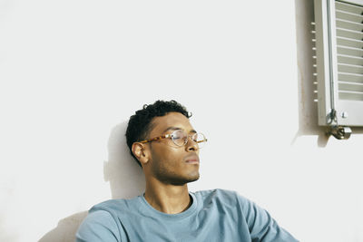 Young man with eyes closed relaxing under sunlight at backyard