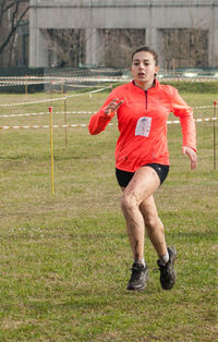 Young female athlete running on field