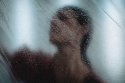 Close-up portrait of woman with reflection on glass