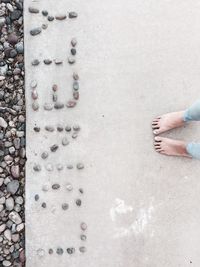 Low section of woman standing by text arranged by pebbles