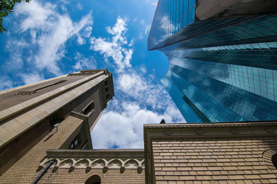 Low angle view of modern buildings against cloudy sky