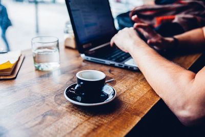 Midsection of woman holding coffee cup on table