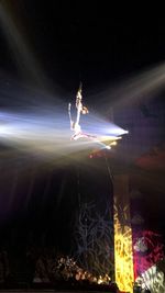 Full length of man standing against illuminated lighting equipment at night