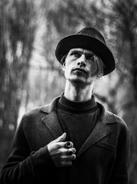 Portrait of man wearing hat standing against trees