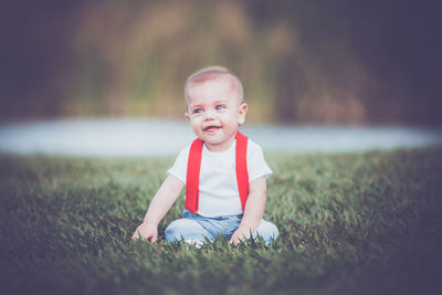 Cute boy looking away while sitting on grass