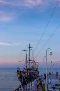 Sailboats moored in sea against sky at sunset