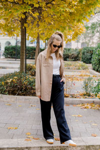 Portrait of young woman standing on footpath