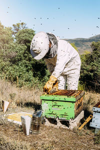 Man working over beehive on land