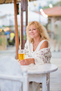 Portrait of woman drinking beer at beach cafe