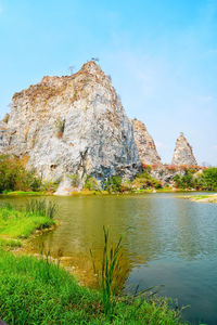 Rock formations by lake against sky