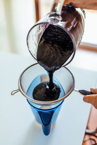 Close-up of hand pouring coffee in glass