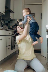 Side view of woman using mobile phone while standing at home