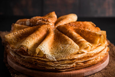 A stack of thin pancakes on a dark wooden background close up. a traditional dish of crepes