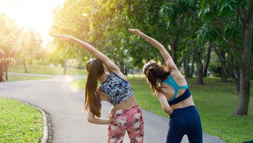 Rear view of female friends exercising on road at park