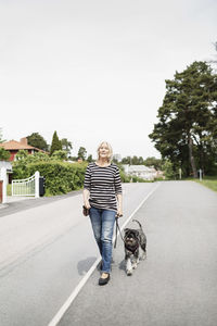 Portrait of woman with dog on road