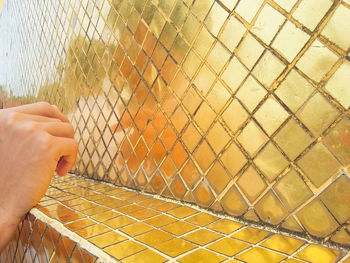 Cropped hand of person by tiled wall