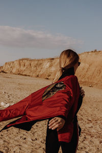 Rear view of woman walking on sand dune