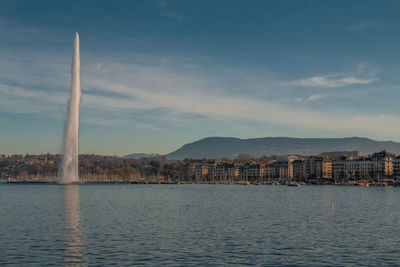 City at waterfront against cloudy sky