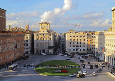 Vehicles on road of piazza venezia amidst buildings in city against sky