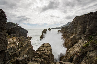 Rock formations by sea against sky