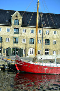 Boats moored in canal by building against sky