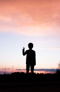 Silhouette man standing on field against sky during sunset