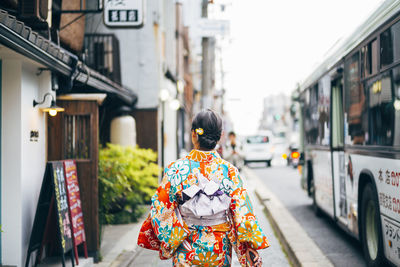 Rear view of woman walking on street in city