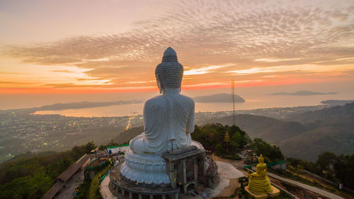 Statue against temple during sunset