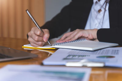 Midsection of man reading book on table