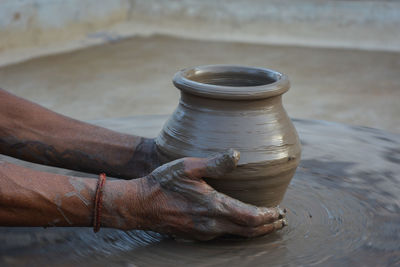 Hands working on pottery wheel and making a pot