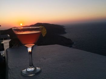 Close-up of wineglass on table against sky during sunset