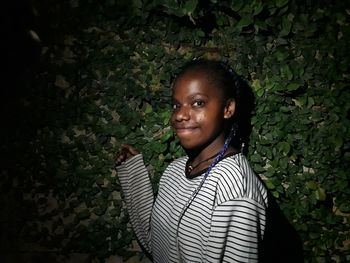 Portrait of young woman standing against plants