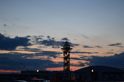 Birds in city against sky during sunset