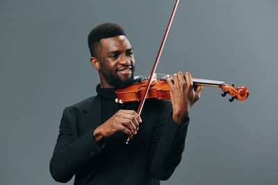 Young man playing violin against white background