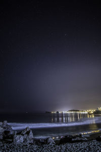 Scenic shot of illuminated beach against sky at night