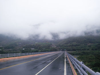 Road leading towards mountain against sky