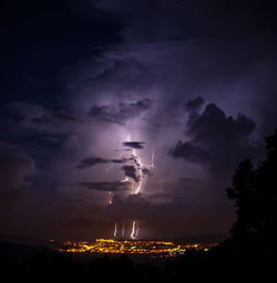 View of illuminated city against cloudy sky