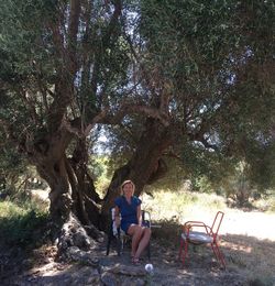 Full length of woman sitting on tree against plants