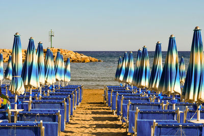 Deck chairs on beach against clear blue sky