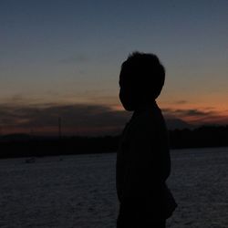 Silhouette of people standing by sea at sunset