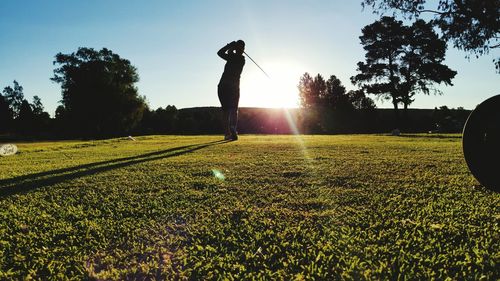 Silhouette person playing golf against clear sky