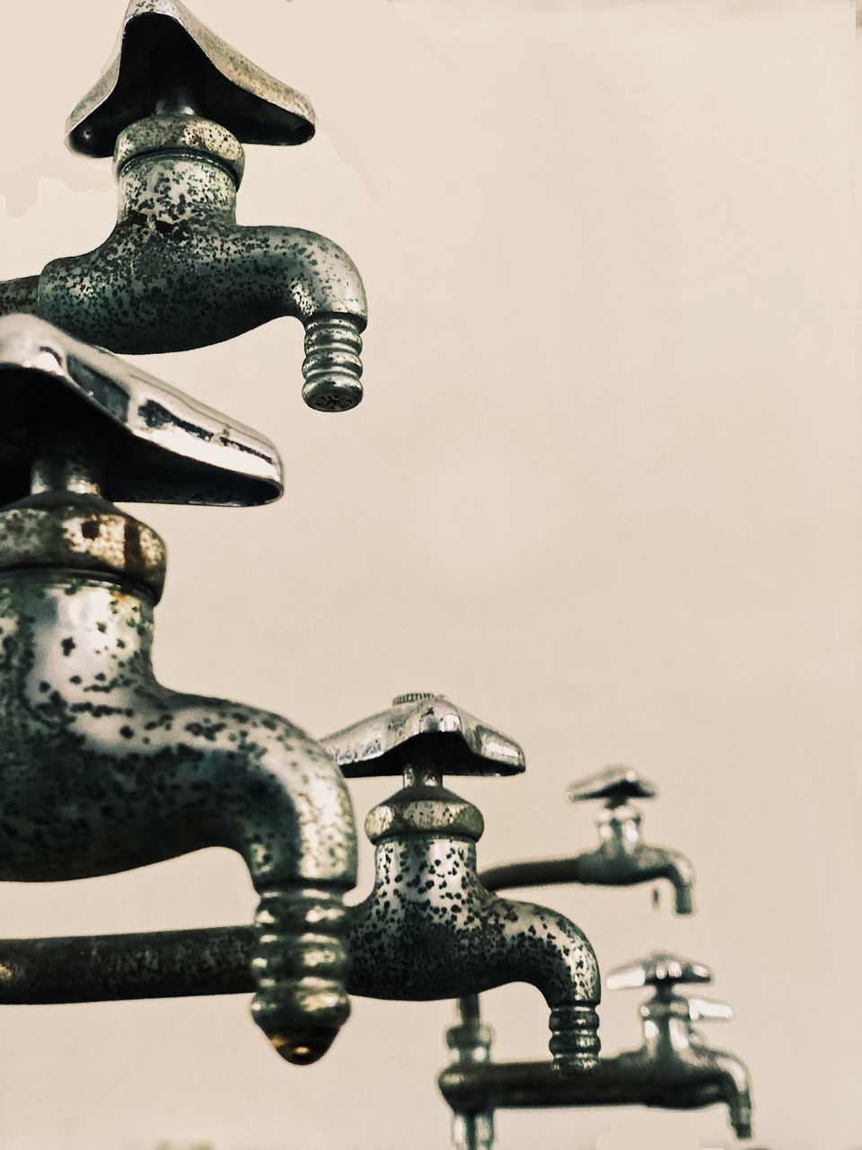 CLOSE-UP OF FAUCET AGAINST WALL AND WHITE BACKGROUND