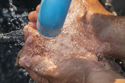 Close-up of hand holding water under pipe