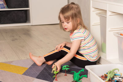 Child playing on the floor in dinosaurs in the room. leisure and education at home