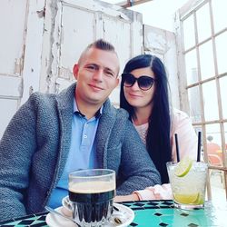 Portrait of young couple sitting with drinks at cafe