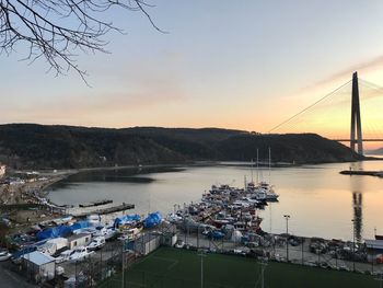 High angle view of harbor by river against sky during sunset