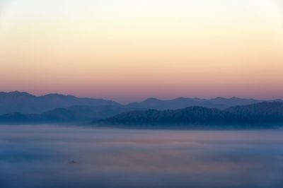 Scenic view of silhouette mountains against romantic sky at sunset