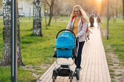 Mom in glasses walks with a stroller in the park